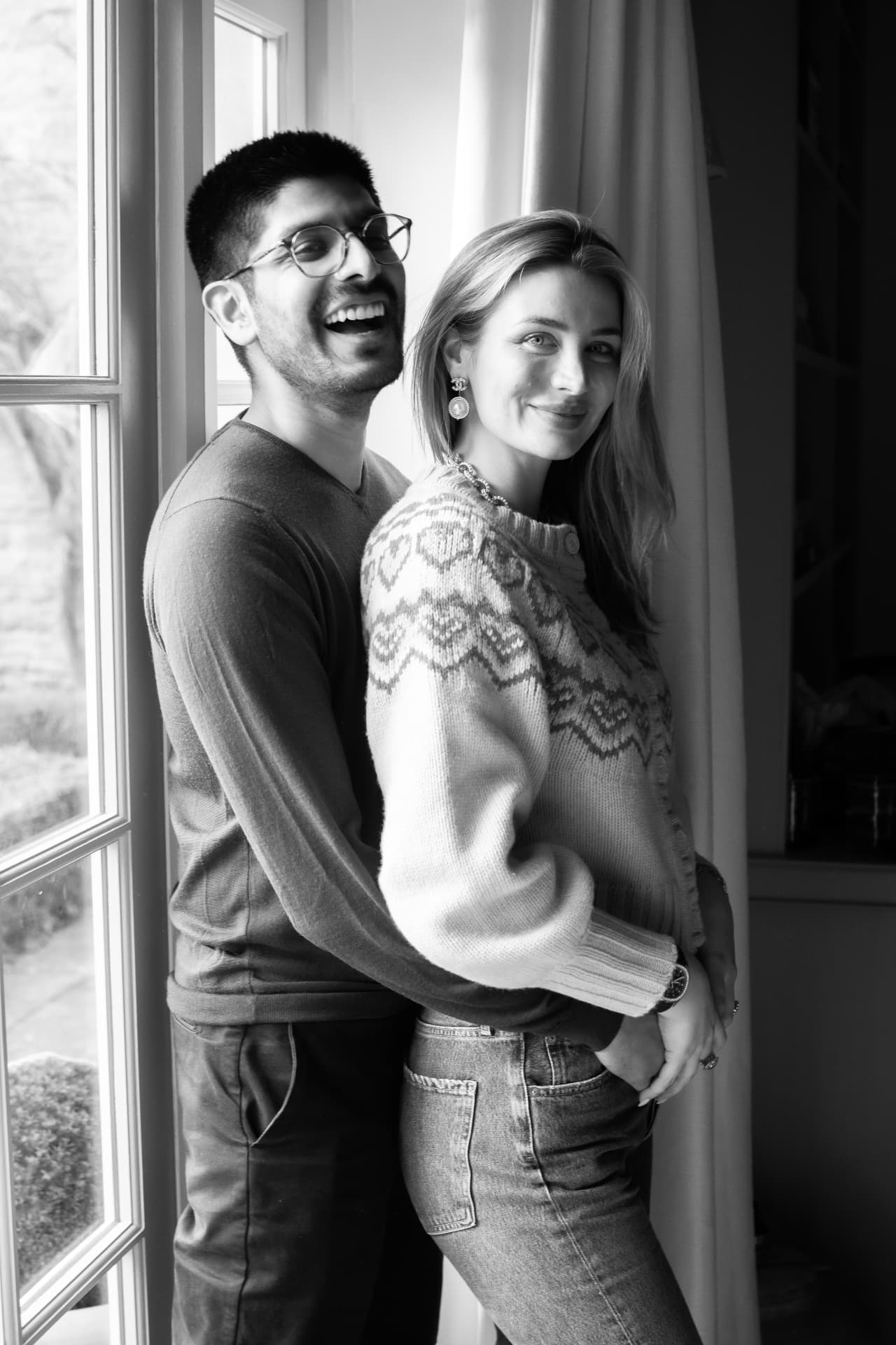 Black and white portrait of a couple standing together by a window