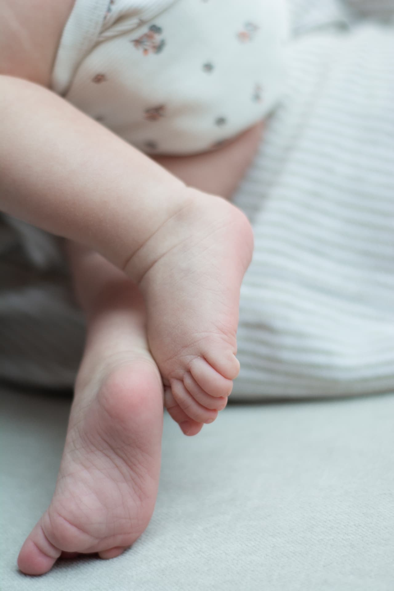 Close-up of a newborn baby's feet crossed at the ankles on soft fabric