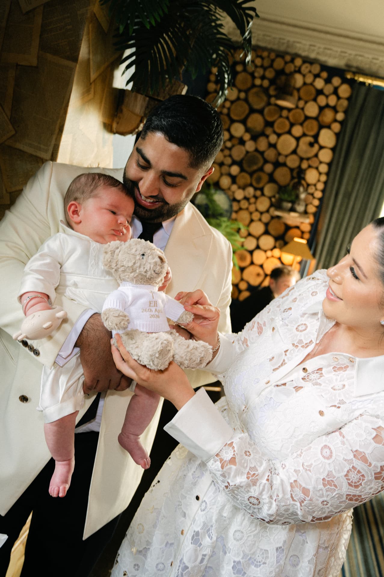 Parents holding their baby and a christening teddy bear