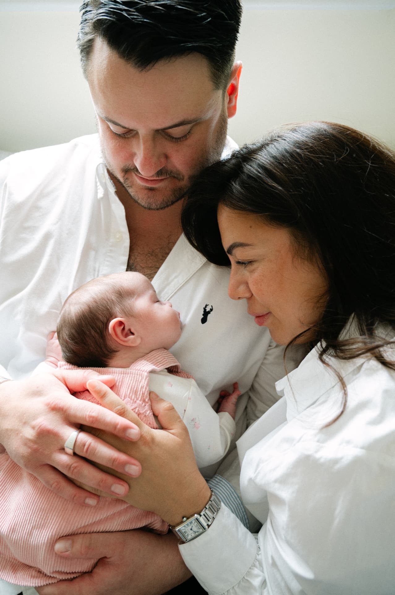Close-up of a mother and father looking down at their sleeping newborn baby
