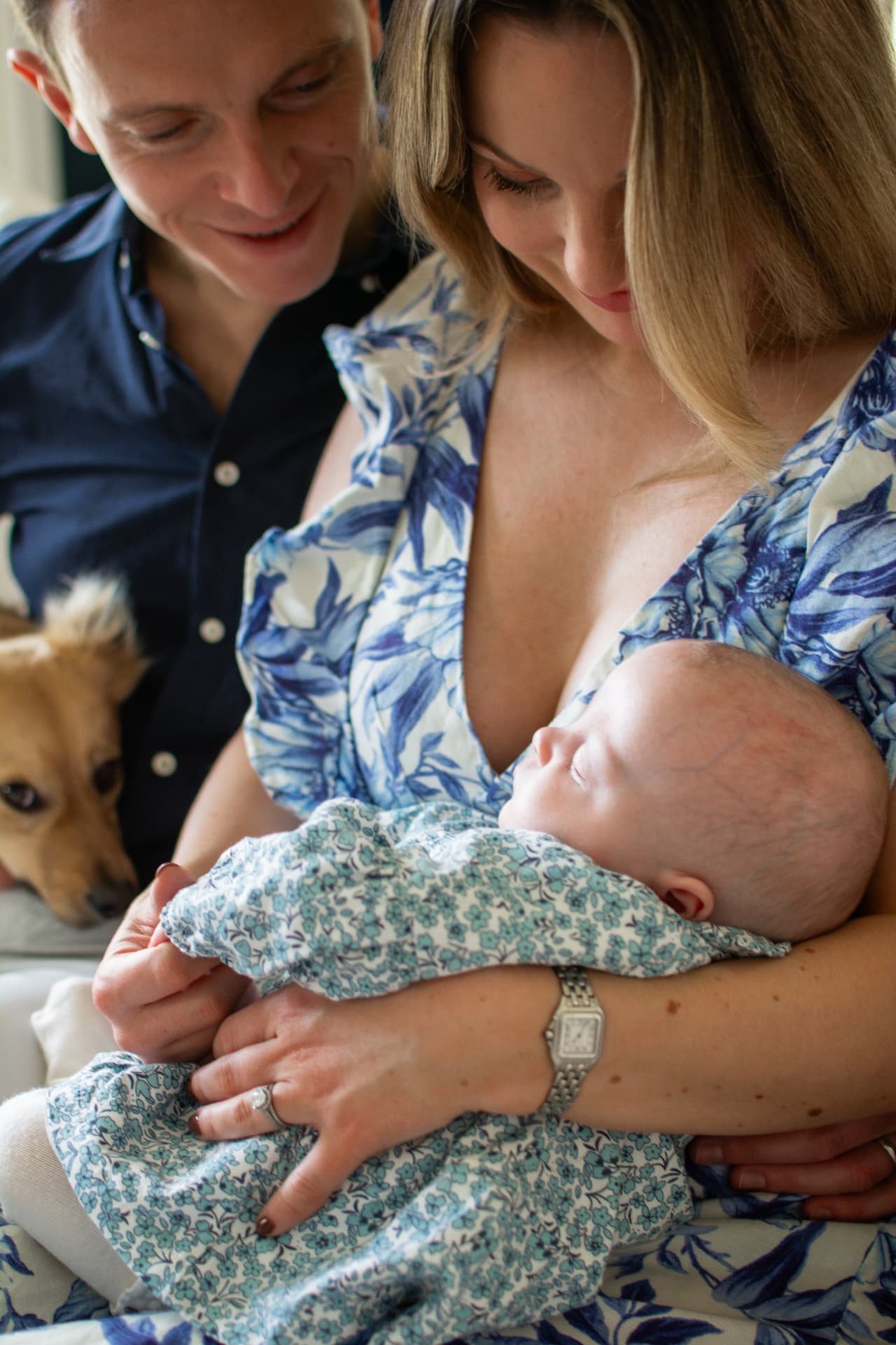 Parents looking down at their sleeping baby with the family dog nearby