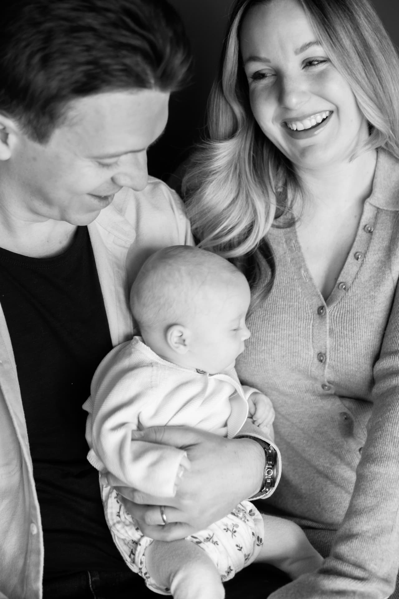 Black and white portrait of parents smiling down at their baby
