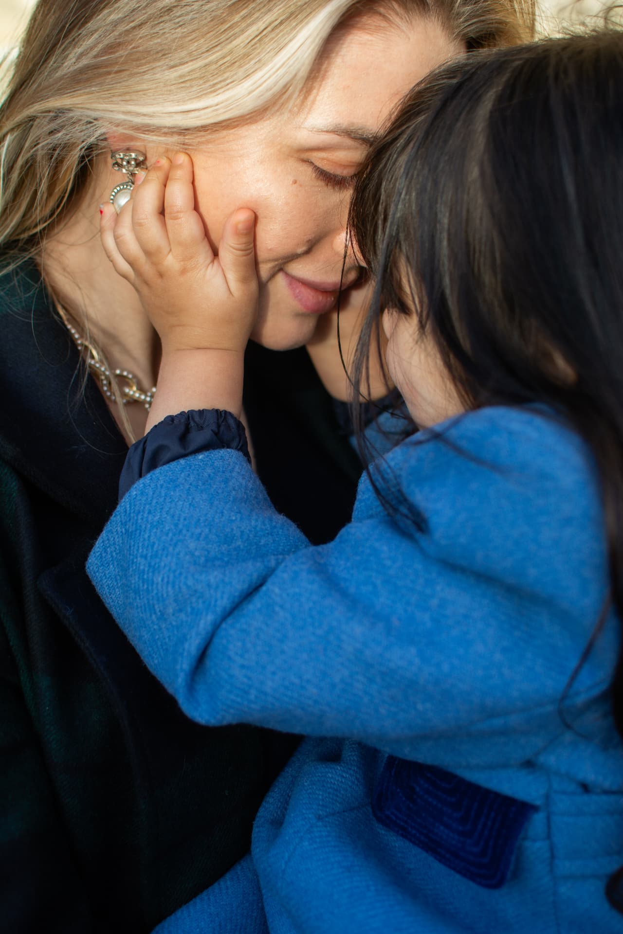Close-up of a child's hand gently touching a mother's face indoors
