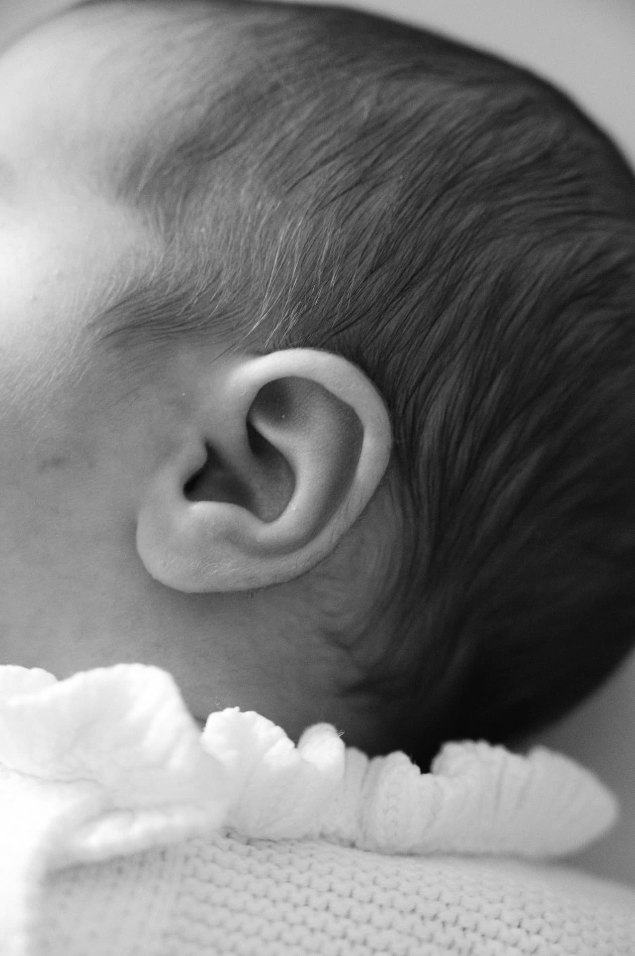 Black and white macro close-up of a baby's ear and the back of their head
