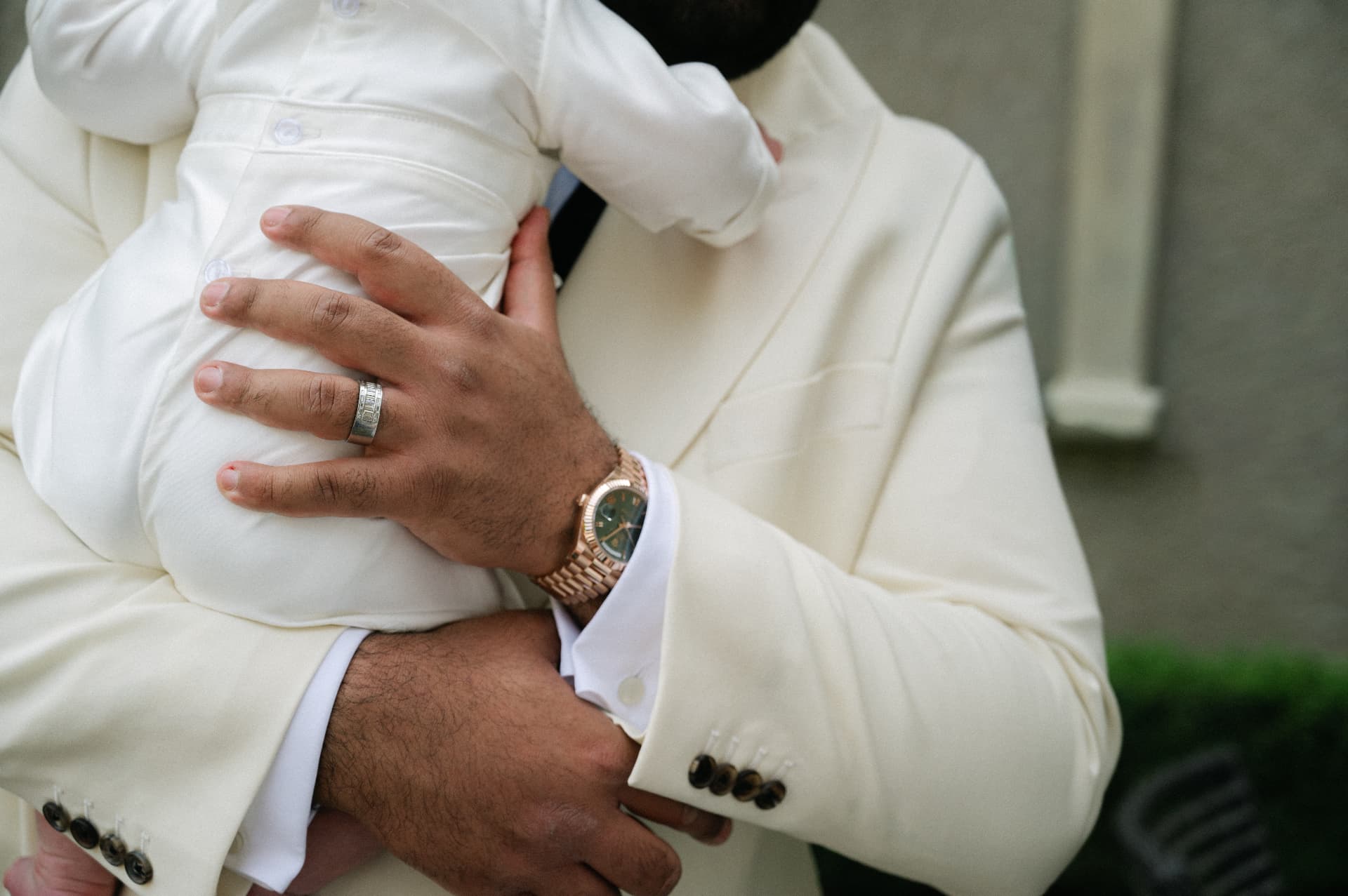 Close-up of a father holding his baby against his cream jacket