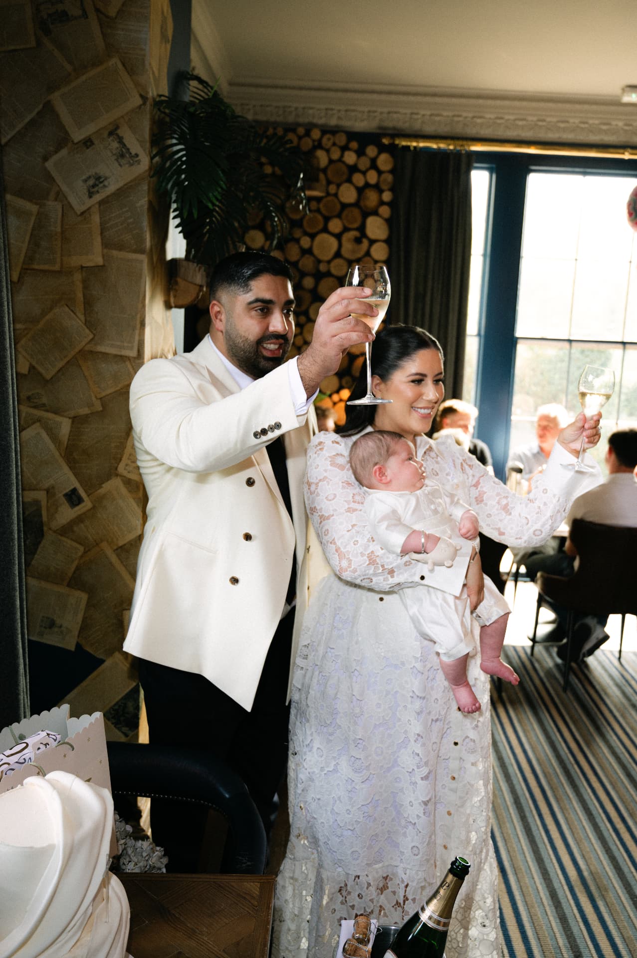 Parents raising a toast while holding their baby at a christening celebration