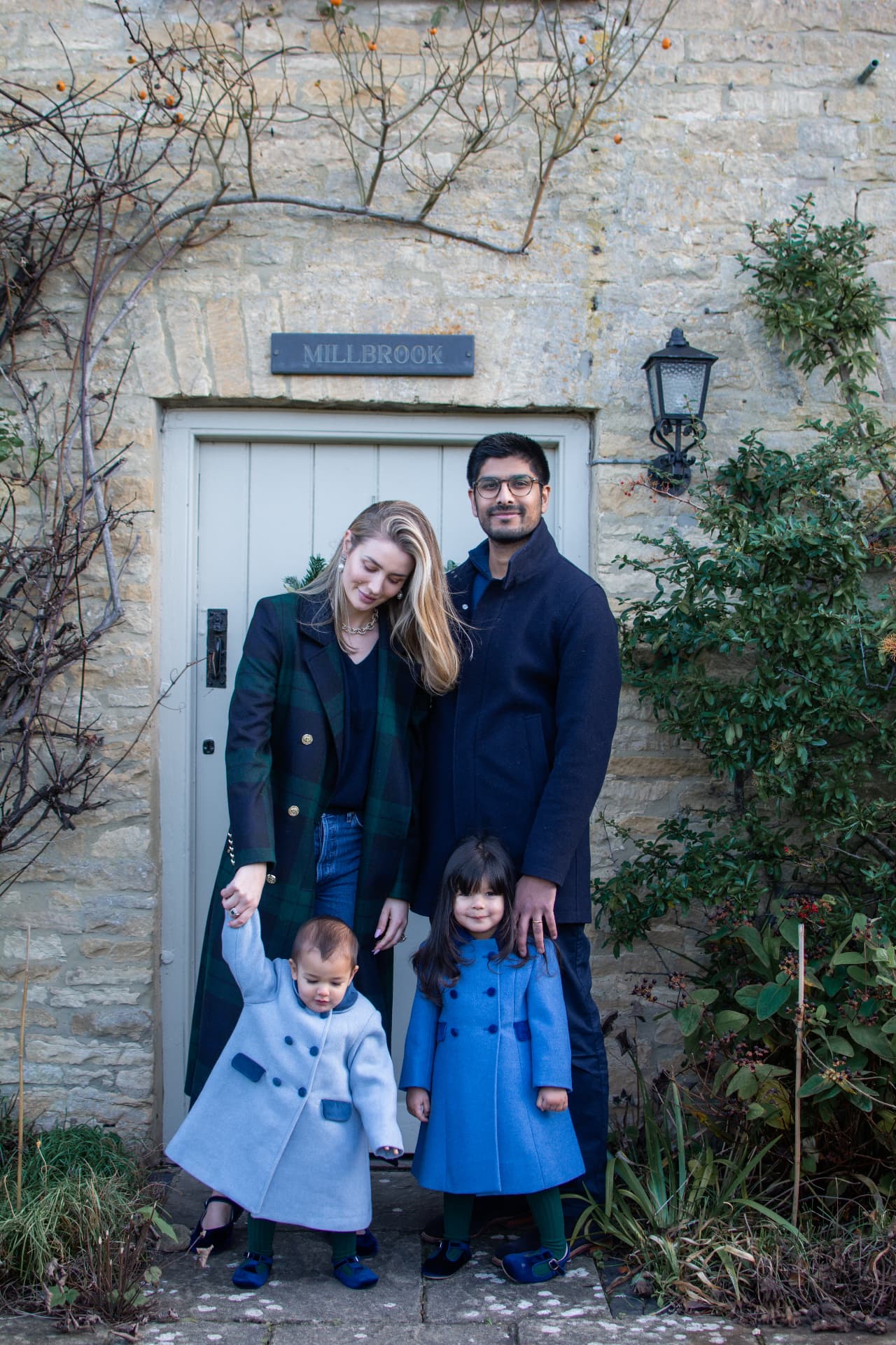 Family of four standing together outside a stone country house