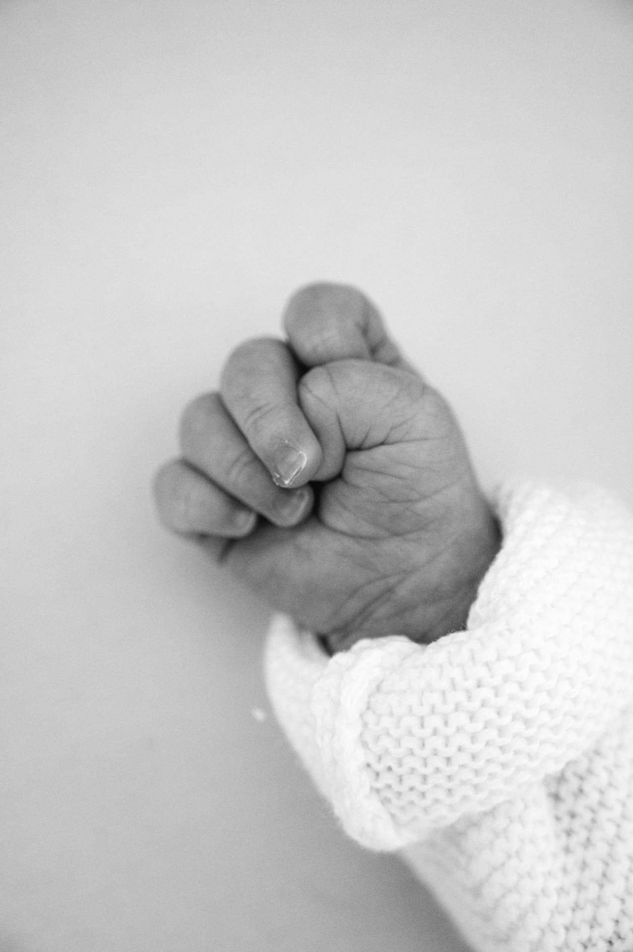 Black and white close-up of a newborn baby's hand curled into a fist