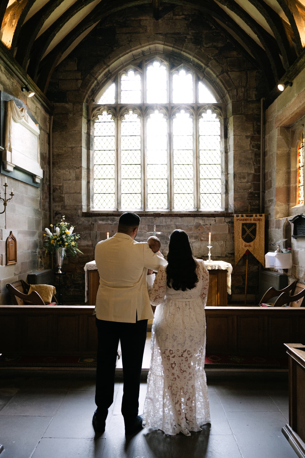 Parents standing with their baby at the altar of a stone church