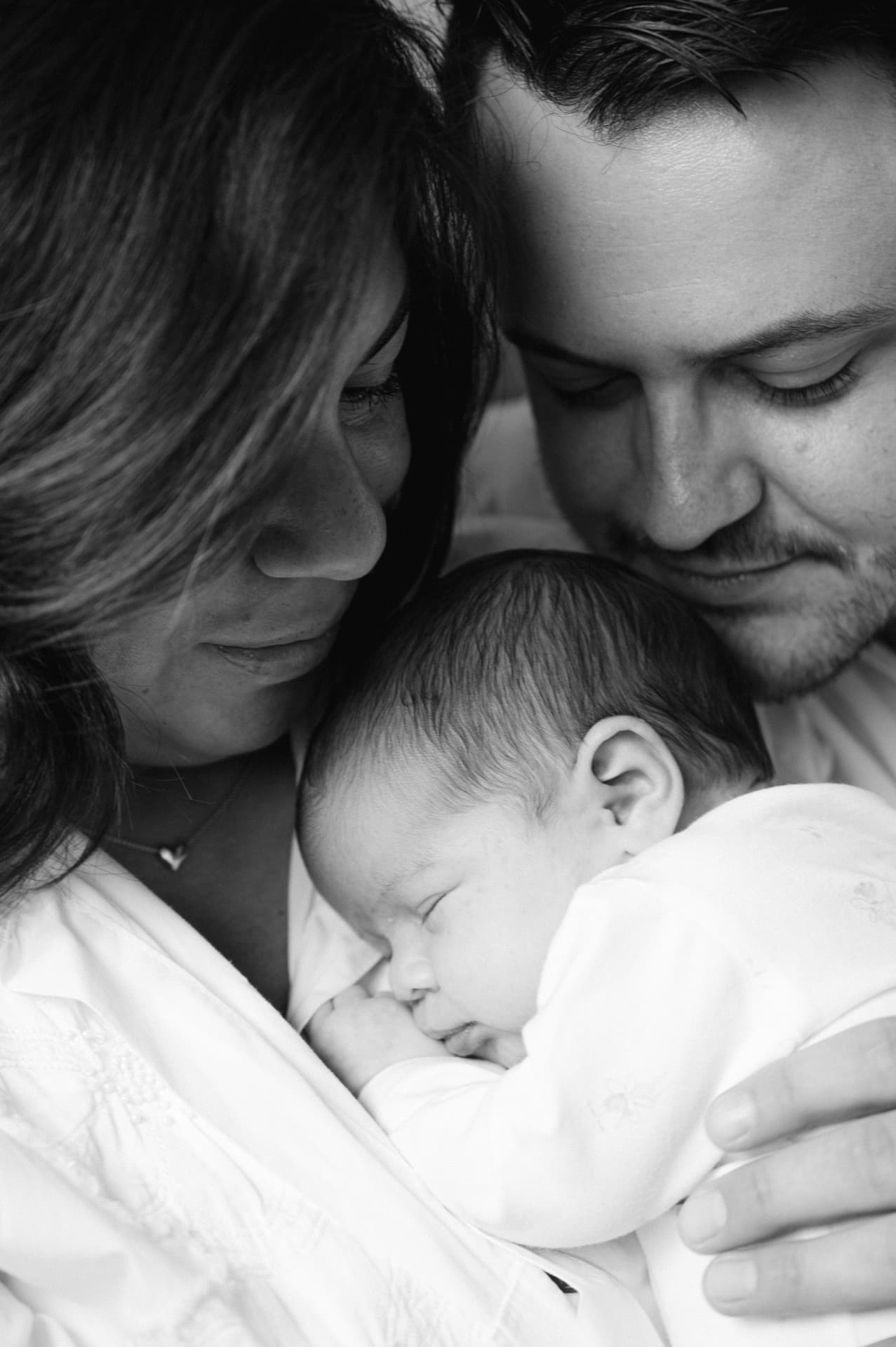 Black and white portrait of parents gazing at their sleeping newborn baby