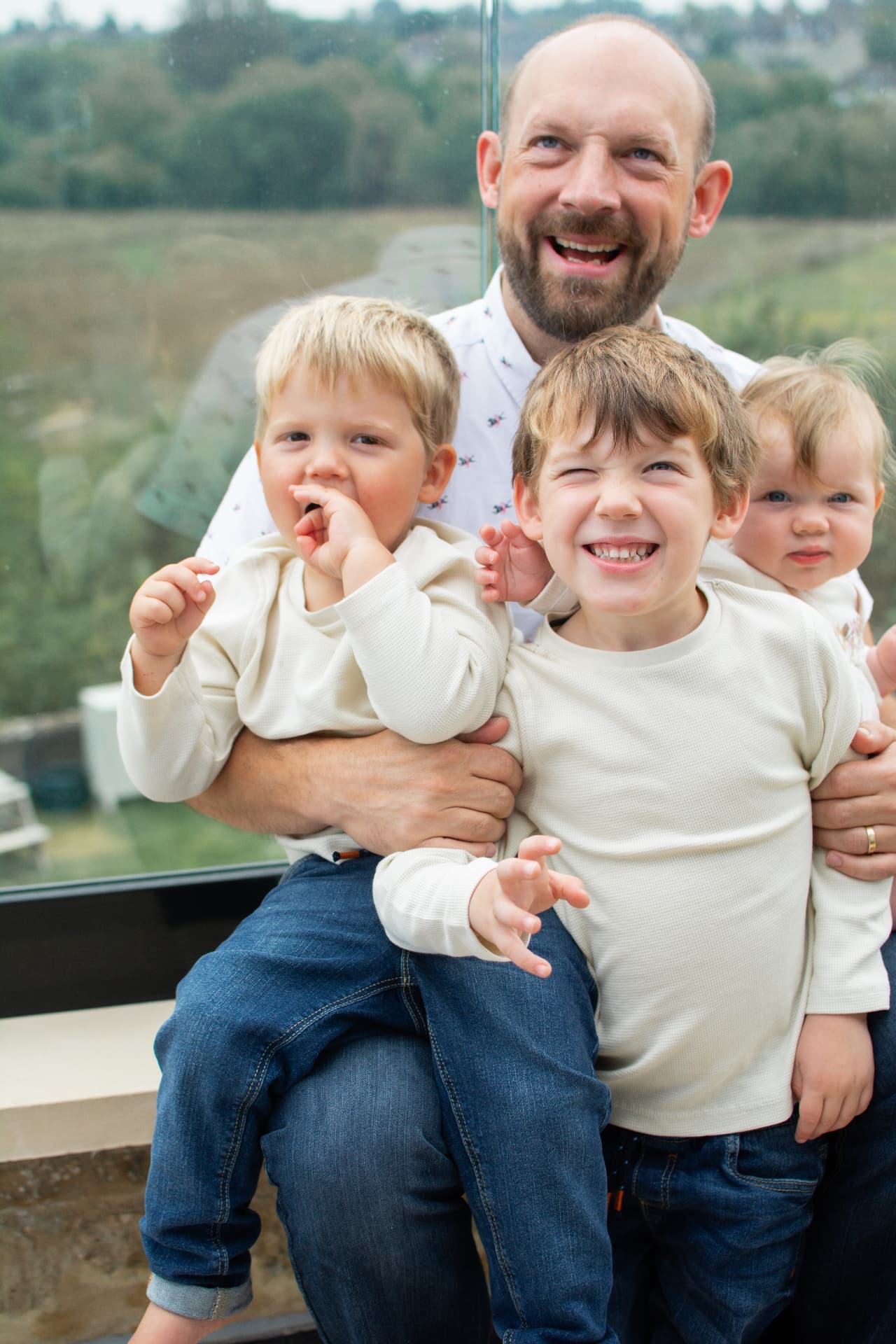 Laughing father with three children on a balcony surrounded by bubbles